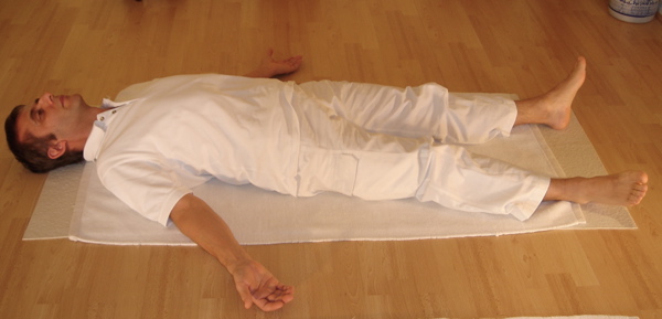 Real photograph of a person resting on their back in Savasana
